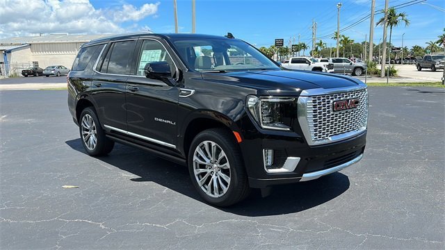 Black GMC Yukon Denali SUV parked in a sunny lot, ideal for luxury limo services.