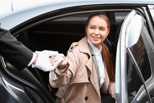 United Limo INC chauffeur in white gloves assisting a woman out of a luxury car in New York.
