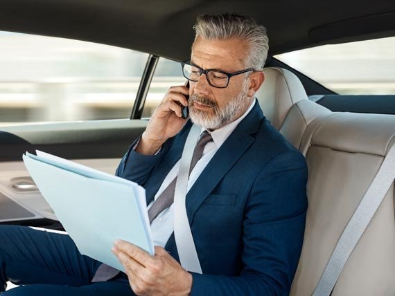Business executive reviewing documents and talking on the phone while riding in a luxury United Limo INC vehicle in New York.