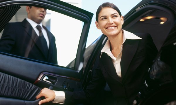 Smiling businesswoman stepping out of a luxury limo with assistance from a professional United Limo INC chauffeur in New York.